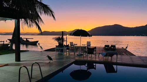 a pool with chairs and a table and an umbrella at EXCLUSIVIDADE à beira-mar in Angra dos Reis