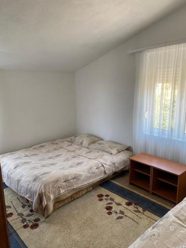 a bedroom with a bed and a table and a window at Apartments Nera in Utjeha