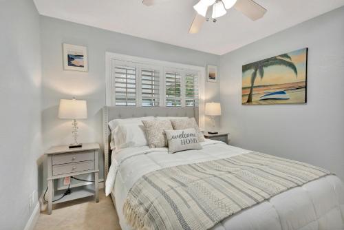 a white bedroom with a bed and a window at Barefoot In Lantana in Lantana