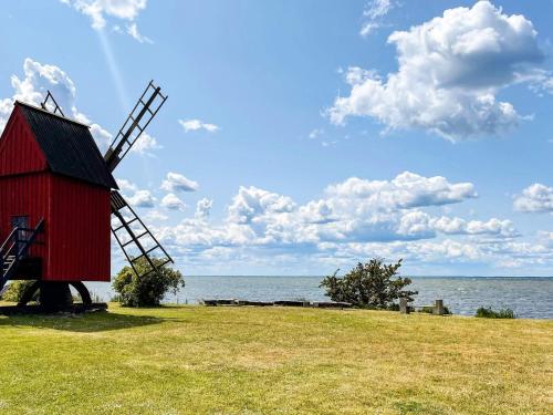 a red windmill sitting on a field next to the water at 5 star holiday home in MÖRBYLÅNGA in Mörbylånga