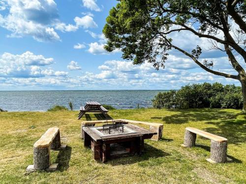 a picnic table and benches next to the water at 5 star holiday home in MÖRBYLÅNGA in Mörbylånga
