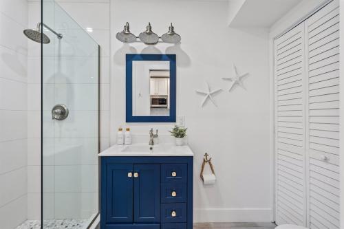 a bathroom with a blue cabinet and a mirror at Sleeps 11 Walk to Atlantic Pool w Sun Deck in Delray Beach