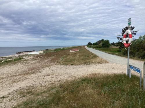 a dirt road next to a beach with a sign at 5 person holiday home in Nakskov in Nakskov