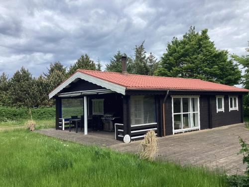 a small house with a wooden deck in a field at 5 person holiday home in Nakskov in Nakskov