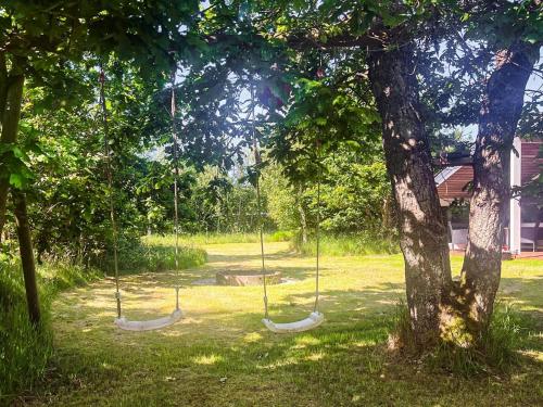 three swings in a park next to a tree at 6 person holiday home in Jerup in Jerup