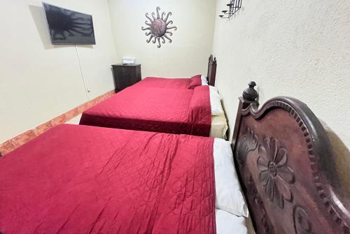 a bedroom with two beds with red comforter at Jireh guesthouse in Antigua Guatemala