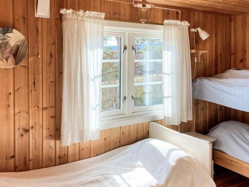 a bedroom with wooden walls and a window and two beds at 6 person holiday home in Røros in Røros