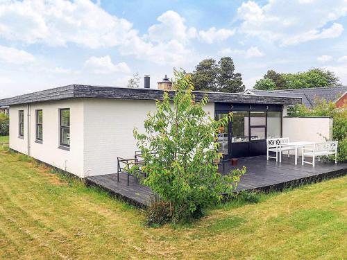 a white house with a deck with a table and chairs at 4 star holiday home in Ålbæk in Ålbæk