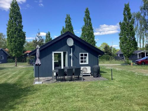 a black shed with chairs and an umbrella at 6 person holiday home in Hovborg in Hovborg