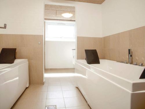 a white bathroom with a tub and a sink at 5 star holiday home in Thyborøn in Thyborøn