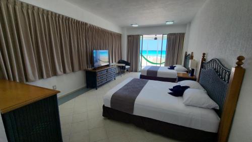 een hotelkamer met twee bedden en een televisie bij Beach Patio Paradise in Cancun