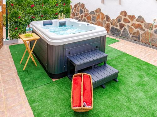 a hot tub sitting on the grass with a red suitcase at Rural House in Moya with Private Jacuzzi in Moya