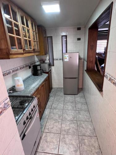 a kitchen with a white refrigerator and wooden cabinets at Hermosa casa en barrio residencial in Santiago