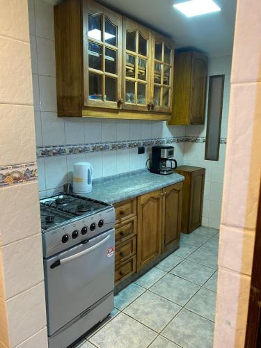 a kitchen with a stove and wooden cabinets at Hermosa casa en barrio residencial in Santiago