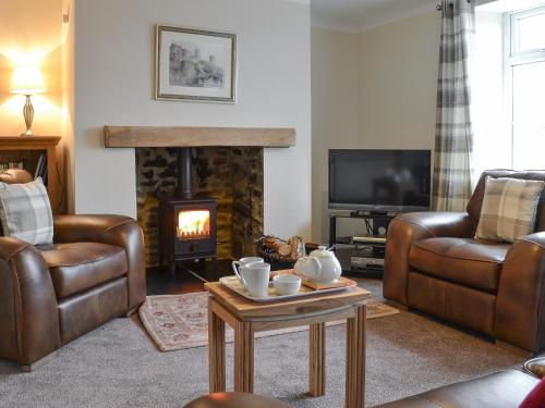 ein Wohnzimmer mit Ledermöbeln und Kamin in der Unterkunft Browney Cottage in Broadwood