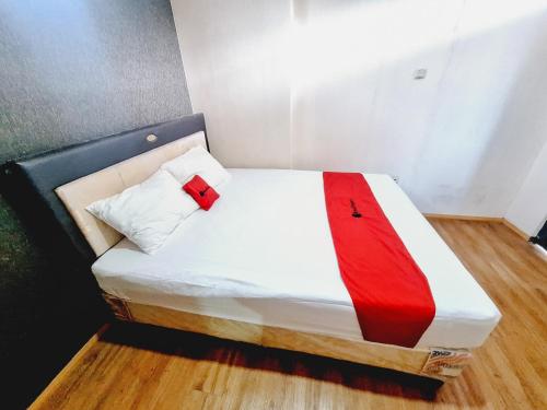 a small bed with a red blanket on it at RedDoorz Syariah near Lippo Plaza Batu in Batu