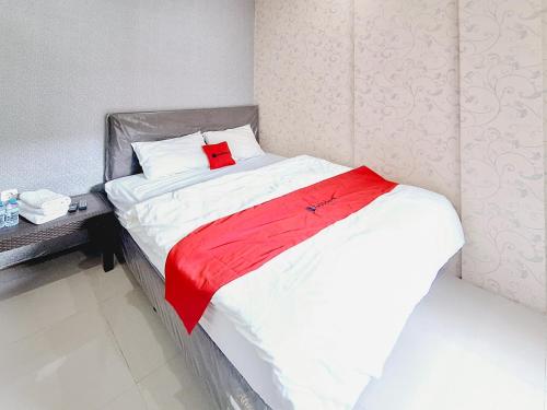 a bed with a red blanket on top of it at RedDoorz Syariah near Lippo Plaza Batu in Batu