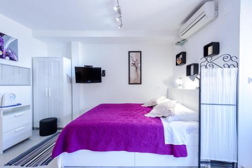 a white bedroom with a purple bed and a tv at Apartment MiNo in Dubrovnik