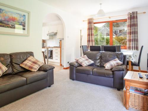 Una sala de estar con dos sofás de cuero y una mesa. en Bidean Cottage - Uk41933, en Glencoe