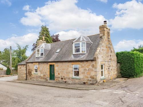 an old stone house with a green door at Holly Tree Cottage in Tain