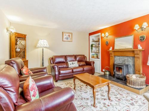 a living room with leather furniture and a fireplace at Holly Tree Cottage in Tain
