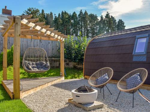 a backyard with two chairs and a wooden pergola at Joshua's Den - Uk40975 in Felindre