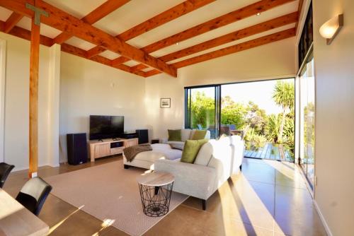 a living room with white furniture and a large window at Te Kahu Pacific View in Whangarei