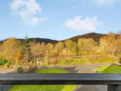 a wooden bench in a park with a mountain in the background at Am Bruadar in Dalmally