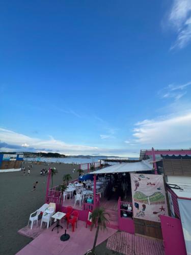 a beach with tables and chairs and people on the beach at Ocean Flat 江ノ島鵠沼海岸 in Fujisawa