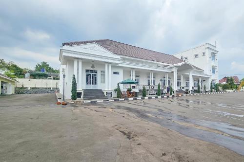 a large white building in a parking lot at Sans Vibes Hotel Sulanjana Syariah Sukabumi in Krawang
