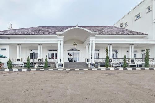 a large white building with a porch and stairs at Sans Vibes Hotel Sulanjana Syariah Sukabumi in Krawang