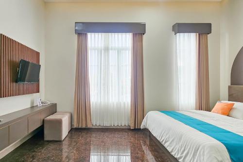 a hotel room with a bed and a tv and window at Sans Vibes Hotel Sulanjana Syariah Sukabumi in Krawang