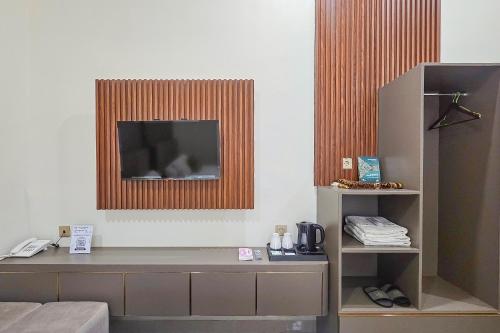a room with a television on a wall with a shelf at Sans Vibes Hotel Sulanjana Syariah Sukabumi in Krawang