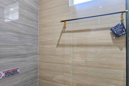 a shower stall with a beige tile wall at Sans Vibes Hotel Sulanjana Syariah Sukabumi in Krawang