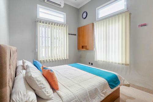 a bedroom with a bed and two windows at Sans Vibes Hotel Sulanjana Syariah Sukabumi in Krawang