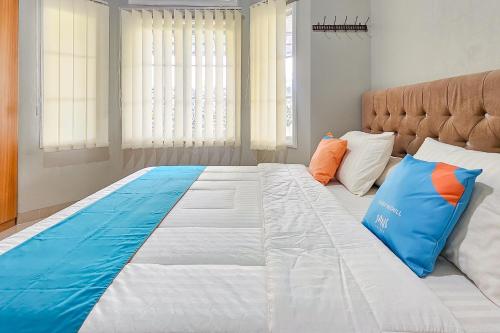 a large bed with blue and orange pillows on it at Sans Vibes Hotel Sulanjana Syariah Sukabumi in Krawang