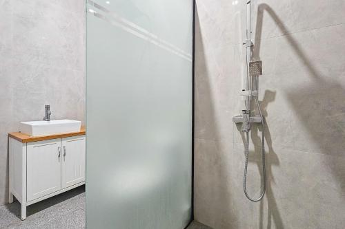 a shower with a glass door in a bathroom at Sans Vibes Hotel Sulanjana Syariah Sukabumi in Krawang