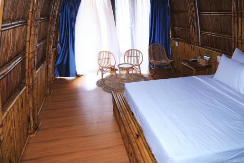 a bedroom with a bed and two chairs and a window at Cat Ba Holiday Retreat in Cat Ba