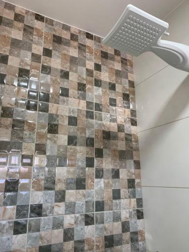 a shower with a checkered tile wall in a bathroom at Pousada Paraíso Goiânia in Goiânia