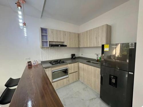 a kitchen with wooden cabinets and a black refrigerator at Casa con Terraza y Vista Espectacular a la Naturaleza in Dosquebradas