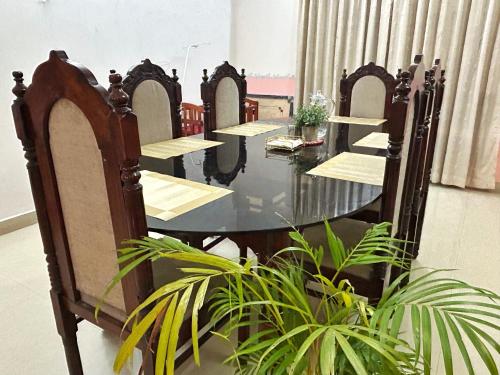 a table with four chairs and a table with plants at La Casa Trivandrum 4 BHK AC Luxury Villa at City Centre, Just 5 kms from Airport & 3 Kms to Trivandrum Railway Station in Trivandrum