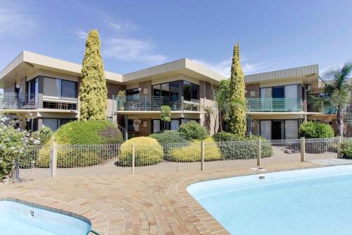 a house with a swimming pool in front of it at Comfort Inn & Suites Lakes Entrance in Lakes Entrance