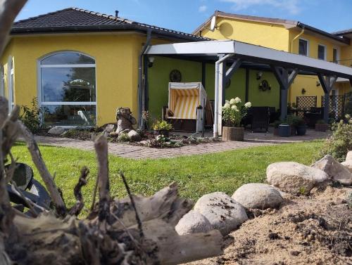 a yellow house with a yard with rocks at Fewo-Nordseeanker in Friedrichskoog