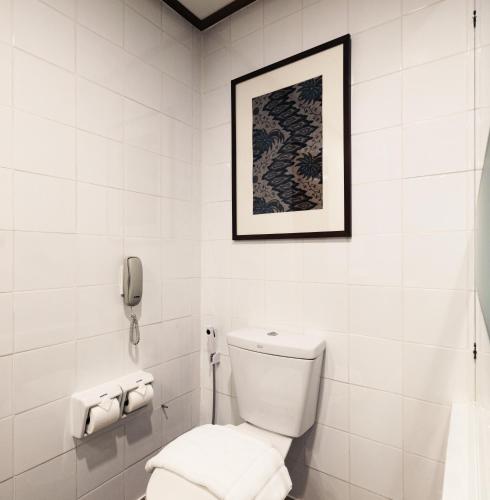 a white bathroom with a toilet and a phone at Royal Phuket City Hotel in Phuket Town
