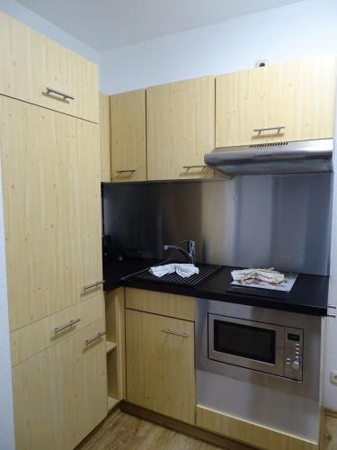 a kitchen with wooden cabinets and a stove top oven at Fewo-Seegras in Friedrichskoog