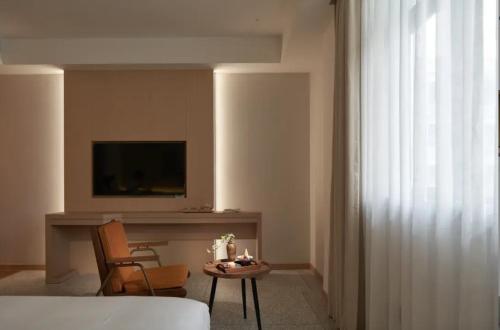 a living room with a table and a tv and a chair at Yinxitang Aesthetic Life Courtyard Hotel Kuanzhai Alley People's Park Subway Station Branch in Chengdu