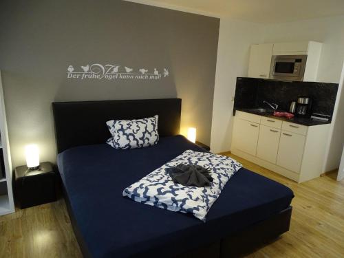 a bedroom with a blue bed and a kitchen at Fewo-Seetank in Friedrichskoog