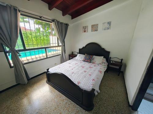 GuayacanaにあるCasa con piscina privada en via flandes espinalのベッドと大きな窓のある寝室
