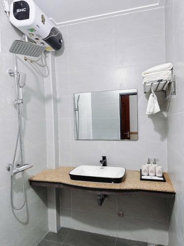 a white bathroom with a sink and a mirror at Bảo Yến HOTEL in Bản Khe Rạn