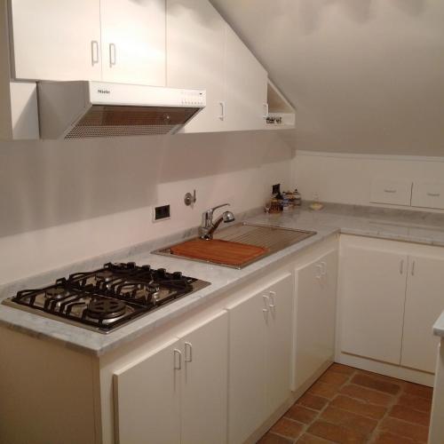 a kitchen with white cabinets and a stove top oven at Locanda Colle Cerqueto in Fiumata
